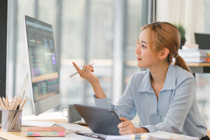 asian woman looking at metrics on monitor